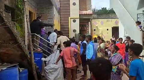 ಕೃಷ್ಣಾನಾಯಕ್ ಕುಟುಂಬ ವಾಸಿಸುತ್ತಿರುವ ಮನೆಯ ಮುಂಭಾಗ ಜನರು ಸೇರಿರುವ ಚಿತ್ರ