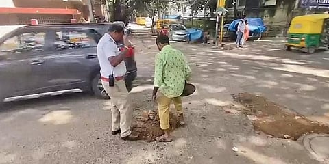 ರಸ್ತೆ ಗುಂಡಿ ಮುಚ್ಚಿಸುತ್ತಿರುವ ಸಂಚಾರಿ ಪೊಲೀಸ್.