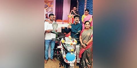 ವಳೂರು ಗ್ರಾಮದ ನಿವಾಸಿಗಳು ಉಡುಗೊರೆಯಾಗಿ ನೀಡಿದ ಬೈಕ್‌ನೊಂದಿಗಿರುವ ಶಿಕ್ಷಕ ಸಂತೋಷ್.